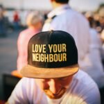 man wearing black cap with love your neighbour print during daytime