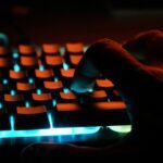 persons hand on blue lighted computer keyboard